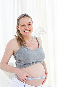 紧贴一个女人的近身 测量她的肚子父母享受客厅母性情感腰部喜悦白色婴儿幸福图片