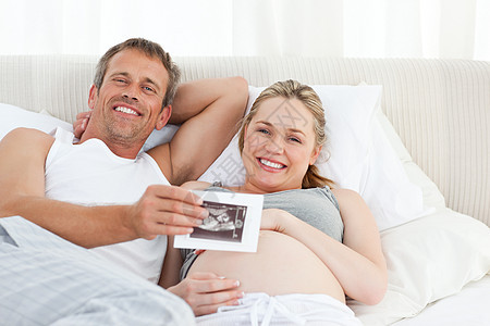 未来的父母看着他们的X光爸爸腹部夫妻几个月母性卧室情感怀孕男人幸福图片