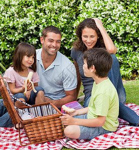 家庭在花园野餐儿子公园午餐篮子女孩水果草地女士父亲娱乐图片
