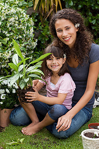 母亲和女儿在花园里工作土壤花园园艺家庭婴儿卷曲土地微笑培育植物图片