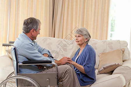 在家起居室说话的年长夫妇保健医疗保险座位截肢车轮退休培育男性轮椅老年图片