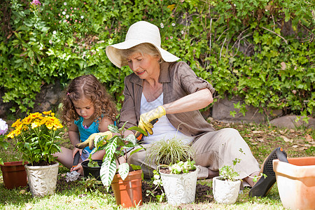 宝宝100天快乐的祖母和孙女 在花园里工作 在花园乐趣帮助微笑家庭幸福植物女性女士成人孩子背景
