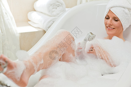 微笑的女人洗个澡 头上戴毛巾护理快乐卫生眼睛温泉洗澡笑脸泡沫女士浴缸图片