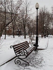 在一个满是雪雪的公园里长椅游客车道降雪天气国家旅行小路孤独季节图片