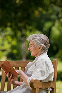退休妇女在法官席上看书公园微笑笑声女士座位小猪肩膀相机农村女性图片