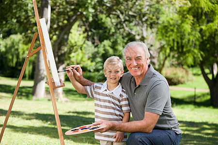 快乐的祖父和他的孙子在花园里画画艺术品后院画架艺术闲暇艺术家享受调色板孙子成人图片
