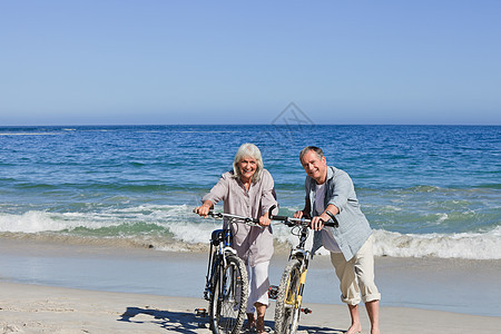 在海滩上骑着自行车的老夫妇运动男人女士婚姻老年祖父家庭祖母已婚丈夫图片