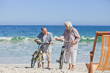 在海滩上骑自行车的老年夫妇在海滩上祖母已婚祖父母闲暇祖父丈夫运动家庭乐趣退休图片