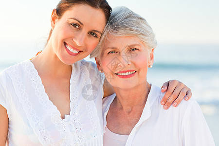 女儿与母亲一起微笑生活海浪家庭甘蔗女士海洋退休老年白色日出背景图片
