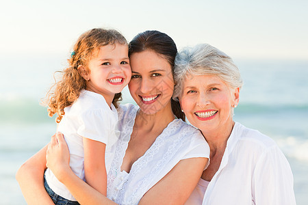 海滩上可爱的家庭海浪日出日落生活女士孙女海岸退休海洋祖母图片