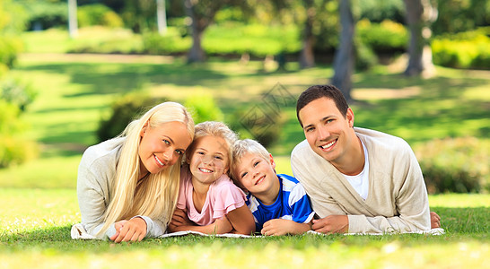 家庭躺在公园里孩子母亲花园父亲儿子享受微笑快乐女儿父母图片