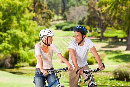 两人在公园里骑着自行车夫妻女士男性幸福微笑享受绿色乐趣相机运动图片