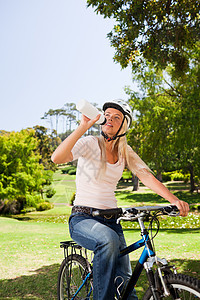 在公园里的女人 骑着自行车享受绿色运动女士锻炼微笑女性幸福乐趣相机图片