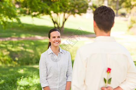 男人给他的女朋友献玫瑰投标周年幸福纪念日公园展示男性女孩女性压痛图片