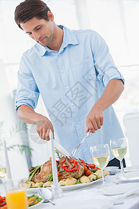 迷人的男子雕刻晚饭男性晚餐盘子微笑白酒感恩快乐餐桌食物房子图片