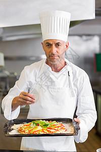 有自信的厨师在厨房吃熟饭工作餐厅围裙烹饪职业准备食物男性制服帽子图片