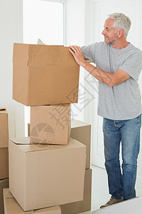 微笑的男人在看纸板移动箱男性搬迁家庭屋主房地产快乐头发住所公寓房子图片