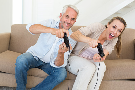 快乐的情侣在沙发上玩电子游戏竞赛夫妻控制器女士家庭乐趣男性娱乐游戏客厅图片