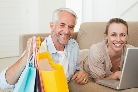 快乐的情侣在沙发上网上购物客厅房子公寓技术零售长椅购物袋成人住所女士图片