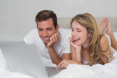 在床上使用笔记本电脑的幸福夫妇图片