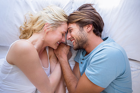 可爱的情侣在床上互相笑笑家庭生活微笑夫妻金发女郎女士男性金发头发拥抱公寓图片
