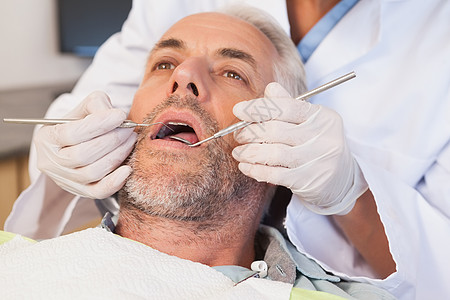 牙科医生检查牙医椅子上的病人牙齒口腔男性手套工作服手术卫生工作牙科考试探针图片