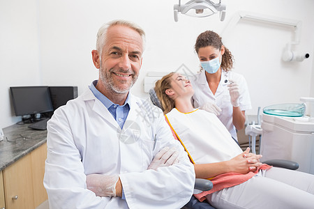 牙医与助手和病人在后面笑着看镜头图片