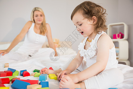 母亲和女儿在床上玩砖块的游戏房子积木童年头发学习模块女孩女性孩子玩具图片