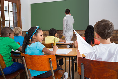 淘气的学生准备在课堂上扔纸飞机快乐孩子小学恶作剧瞳孔早教童年班级女孩工作图片