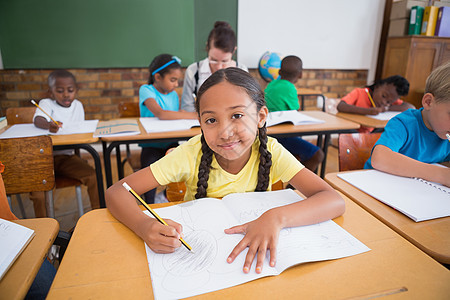 在课堂桌上写字的可爱学生早教工作瞳孔学习小学生童年女孩桌子小学同学们图片