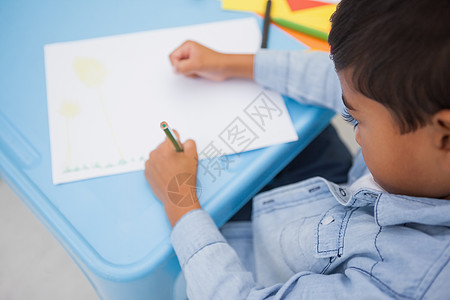 可爱的小男孩在书桌上画画微笑男生童年班级快乐教育创造力课堂绘画艺术背景图片