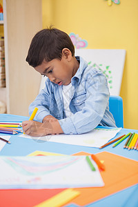 可爱的小男孩在书桌上画画混血绘画艺术童年教育课堂男生铅笔微笑幼儿园背景图片