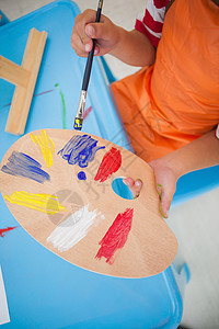 在教室的桌子上画可爱的小男孩童年男生男性早教画笔围裙黄色红色创造力课堂图片
