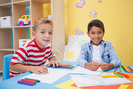 可爱的小男孩在书桌上画画男性教育彩色微笑幼儿园男生铅笔创造力友谊快乐背景图片