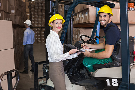 仓库经理与叉车司机对着镜头微笑头盔工人体力劳动者运输机器职业老板女士配送商业图片