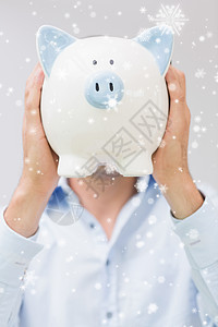 假人当着面拿着小猪银行的一副综合形象男人存钱罐男性衬衫硬币储蓄金融下雪闲暇蓝色图片