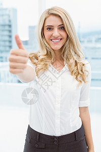 美丽的女商务人士在办公室里挥着大拇指背景图片
