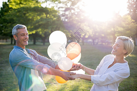 在公园玩得开心的情侣气球自由女性活动感情阳光成人环境娱乐微笑图片