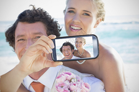 情侣在智能手机上自拍夫妇开端婚姻波浪花束棕色头发技术金发海滩图片