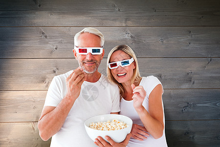 幸福的情侣穿着3D眼镜吃爆米花的综合画面浅色女性剥离感情计算机木头夫妻背心服装微笑图片