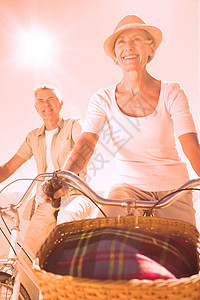 快乐的老年情侣去骑自行车衬衫头发棉布裤草帽闲暇男性微笑阳光女性退休图片