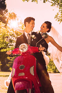新婚夫妇坐在公园的摩托车上套装微笑女性乐趣男性面纱庆典女士婚礼团结图片