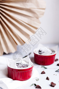 红杯的巧克力松饼 灰色和白色背景的棕色蛋糕 小玻璃陶瓷拉面盘子糖果糕点美食制品杯子食物食谱餐巾餐具图片