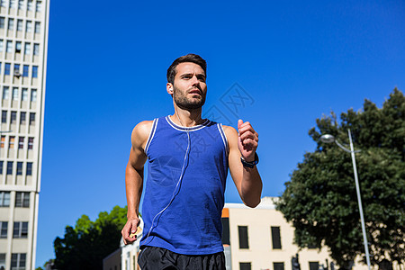 帅美运动员在蓝天上慢跑都市耳机建筑手表风光跑步晴天男人背心护理图片
