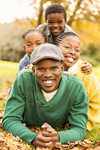 一个微笑的年轻家庭的肖像 躺在树叶上草原草地女性闲暇公园衣服乐趣男性母亲幸福图片