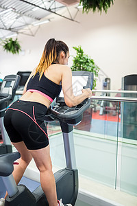 骑自行车看电视屏幕的女运动员竞技运动机身体女性护理锻炼运动服俱乐部健身运动图片