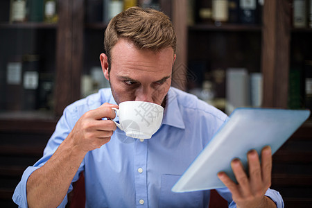 商务人士在喝咖啡时使用数字平板电脑人士男人顾客时间时光休闲杯子触摸屏餐厅咖啡图片