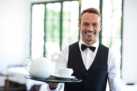 服务员对镜头微笑杯子男人酒店男性马甲餐厅衬衫领结托盘服务图片