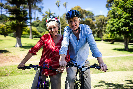 快乐的一对夫妇在公园骑自行车活动闲暇草地农村退休微笑夫妻男性老年人娱乐图片