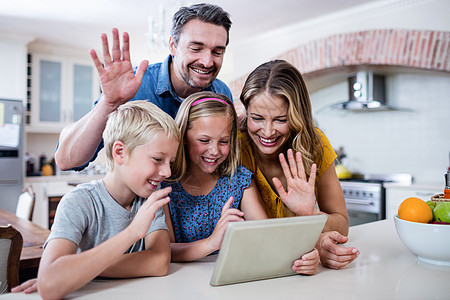父母和孩子在使用数字平板电脑进行视频聊天时手挥手 同时举手图片